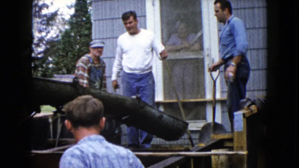1960 Wauconda construction footage shows workers near a concrete chute, wood formwork, and house porch during a pour.