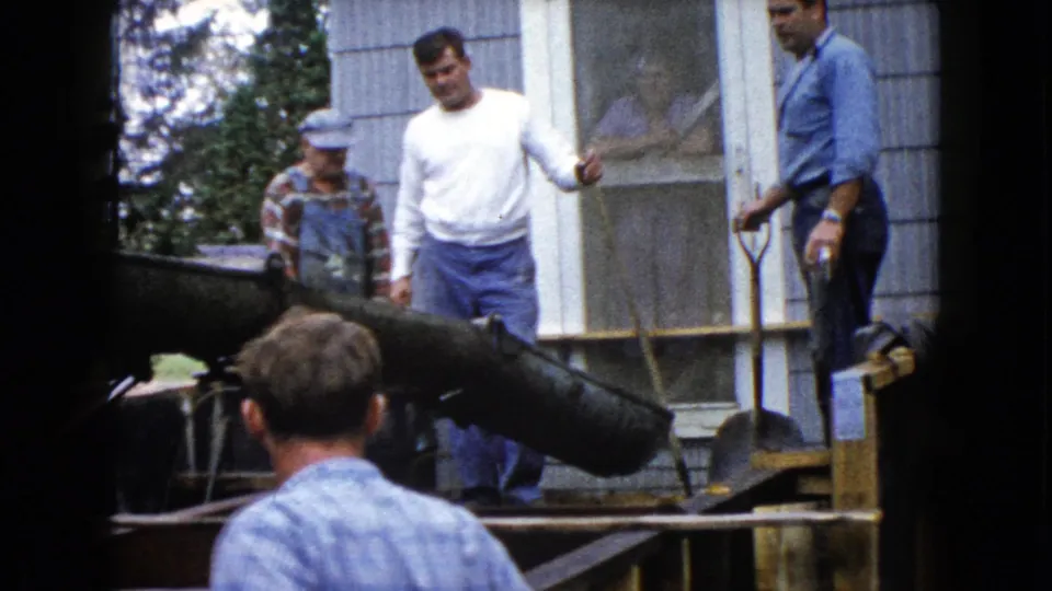 In this 1960 Wauconda frame, workers remain beside the concrete chute, shovel, and wooden forms at a house site.