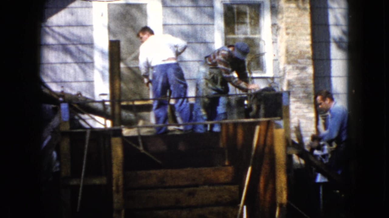 Three men working on a wooden porch outside a clapboard house.