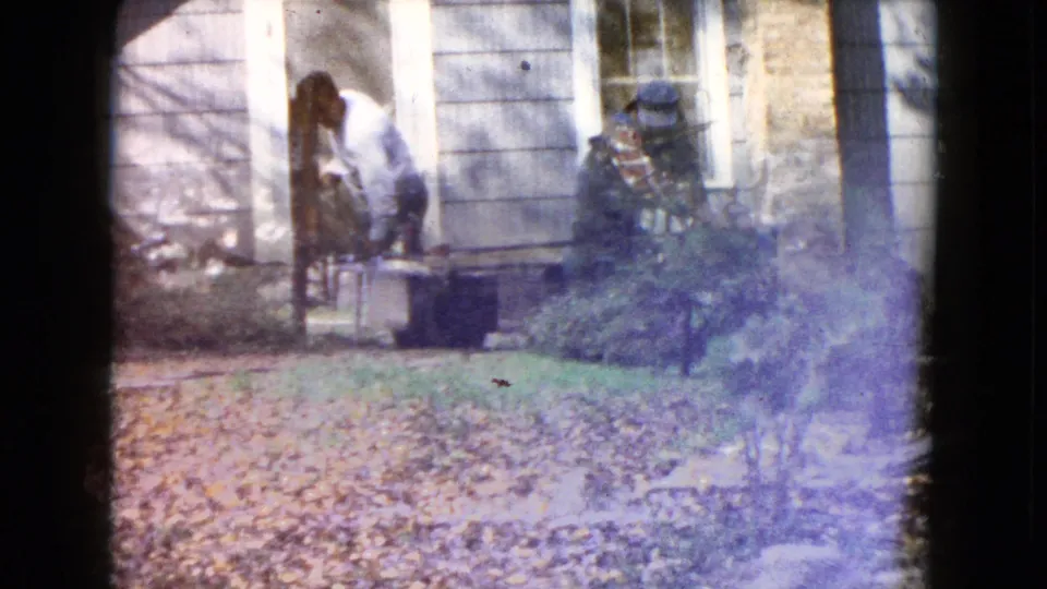 The men continue the house-moving work near the platform and yard, with autumn leaves and film haze visible in the 1960 Wauconda footage.