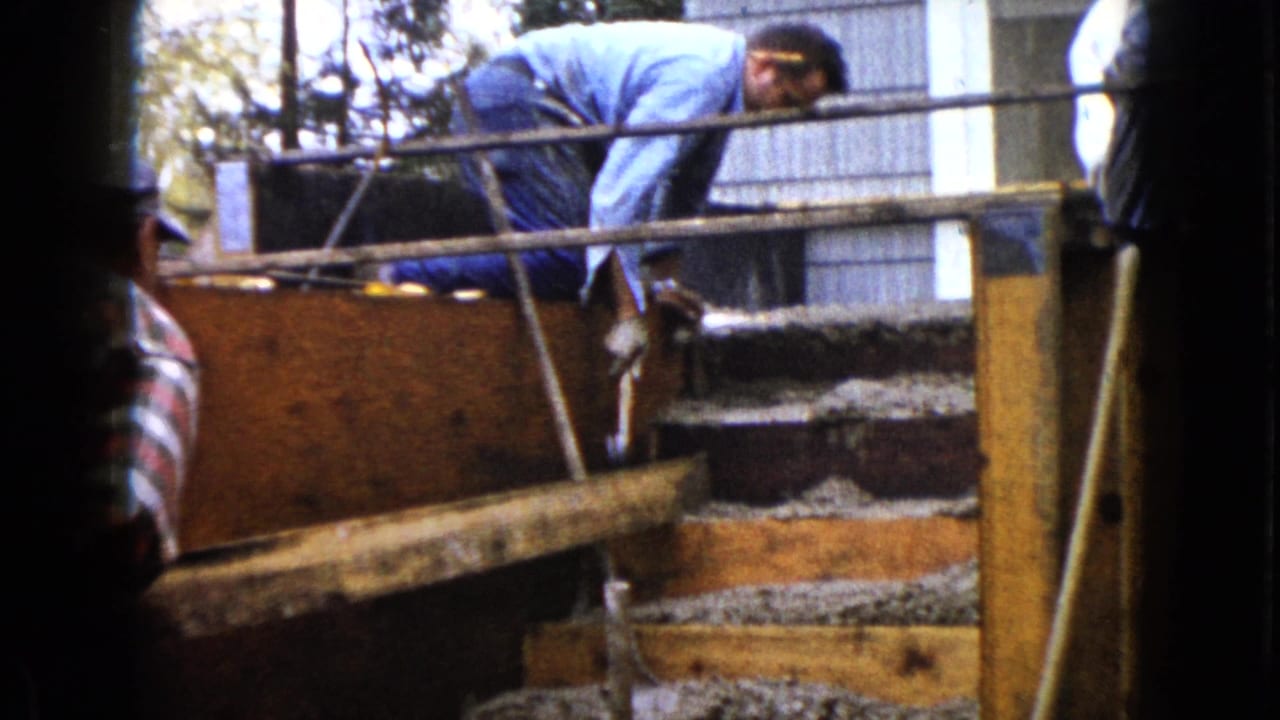 Two men work around wooden concrete step forms at a residential construction site.