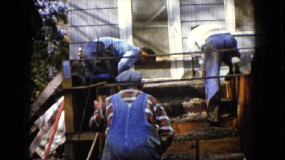 At the end of the short 1960 Wauconda clip, three men continue work around wet concrete steps and porch railings outside a house.