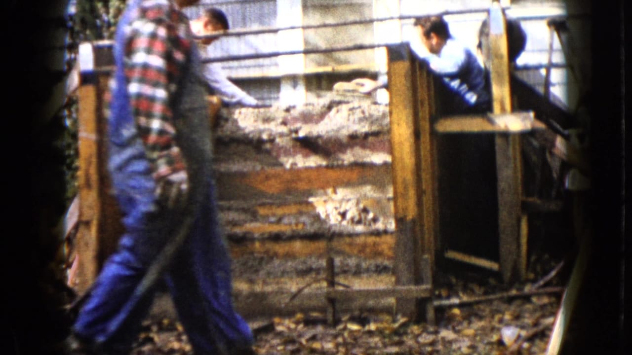 In Wauconda, Illinois, 1960 home-movie footage, men work around wooden forms for concrete steps beside house siding.