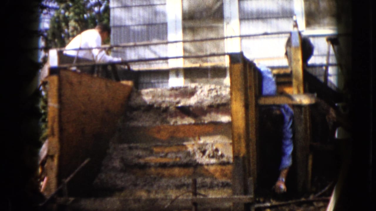 Wauconda, Illinois 1960 frame with rough concrete steps, wood supports, and a partly obscured worker beside the house.