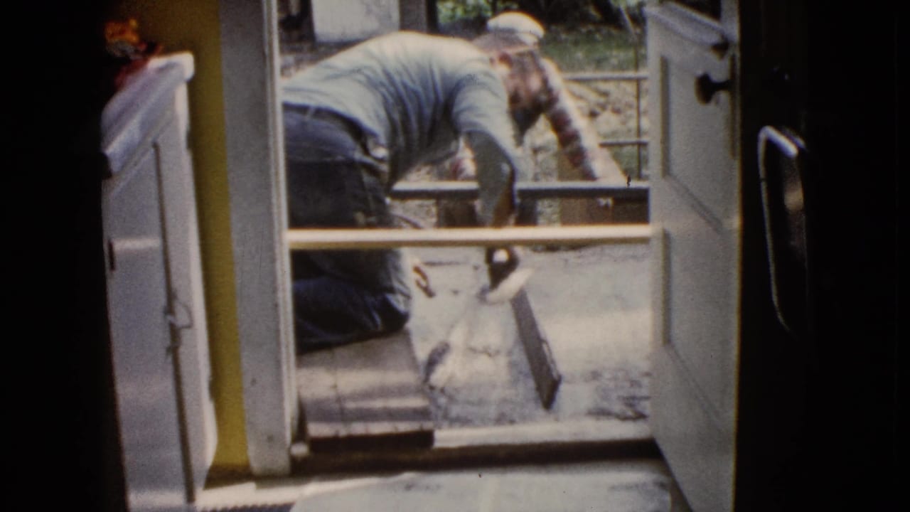 A man leans near the doorway while another works beyond the threshold.