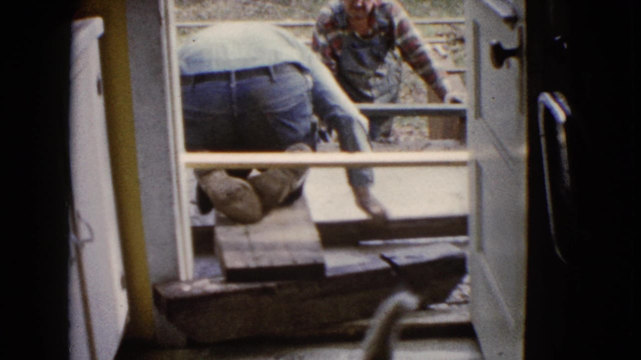 Viewed from inside a doorway in Wauconda, Illinois, one man kneels near the threshold while another works beyond the concrete form.