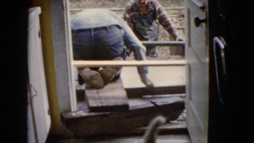 Viewed from inside a doorway in Wauconda, Illinois, one man kneels near the threshold while another works beyond the concrete form.
