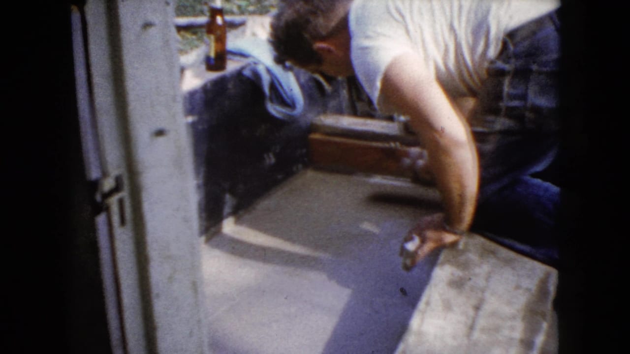 Man works close to a concrete edge with a bottle visible behind him.