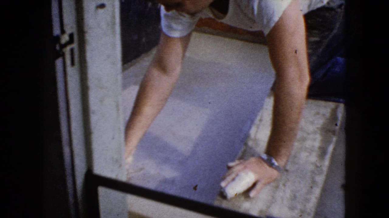 Man leans over the concrete step with both hands near the wet surface.