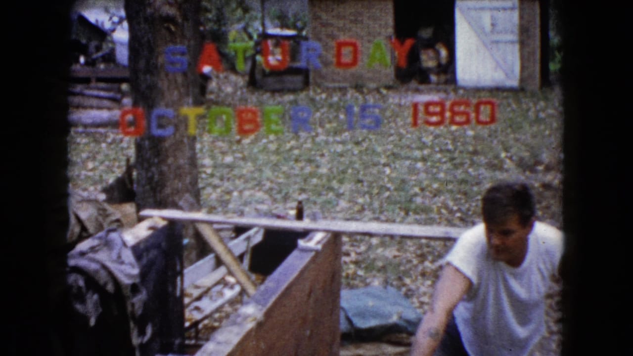 At the end of the 1960 Wauconda clip, the man remains beside the wooden work area with trees, leaves, and date letters in view.