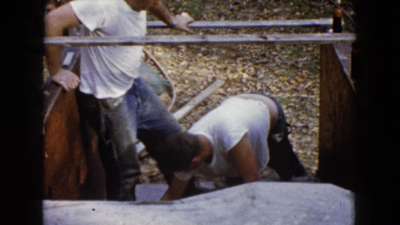 One man stands while another bends over fresh concrete steps.
