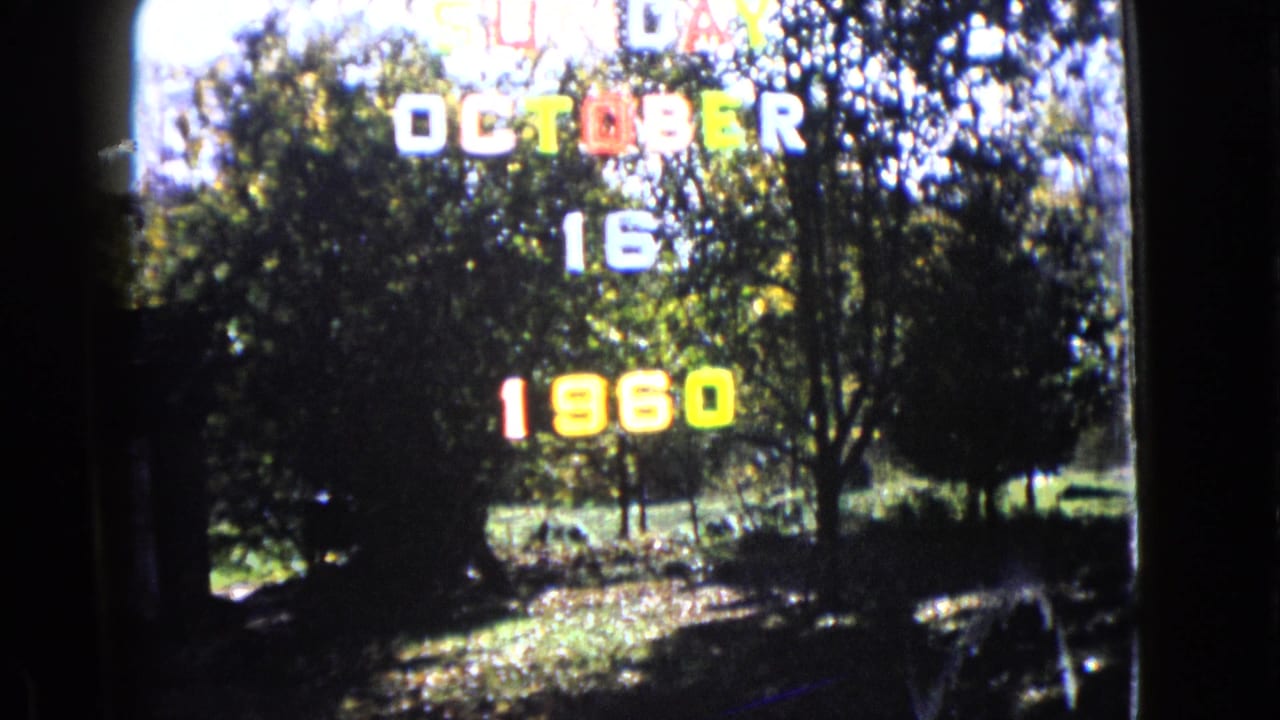 A 1960 home-movie date title overlays shaded trees and grass, with visible 8mm softness and contrast.