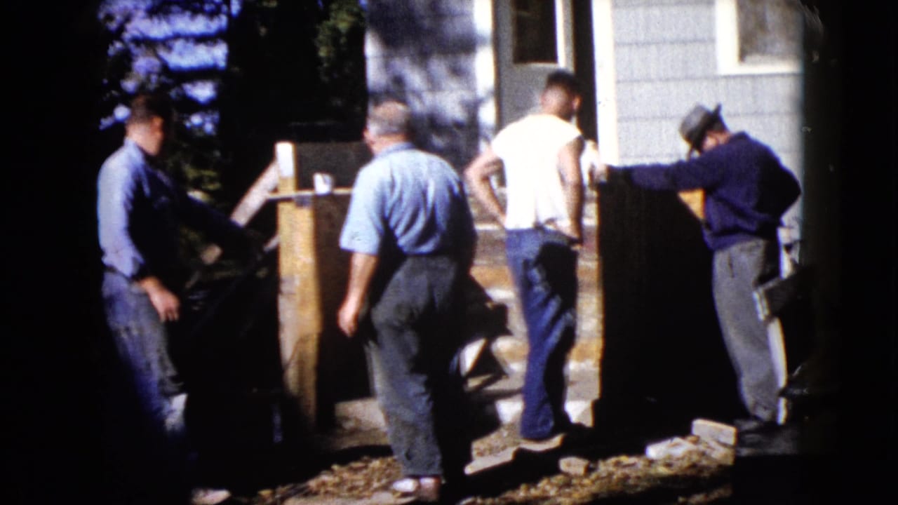 Four adult men appear around wood boards and steps during an outdoor improvement project at a Wauconda home in 1960.