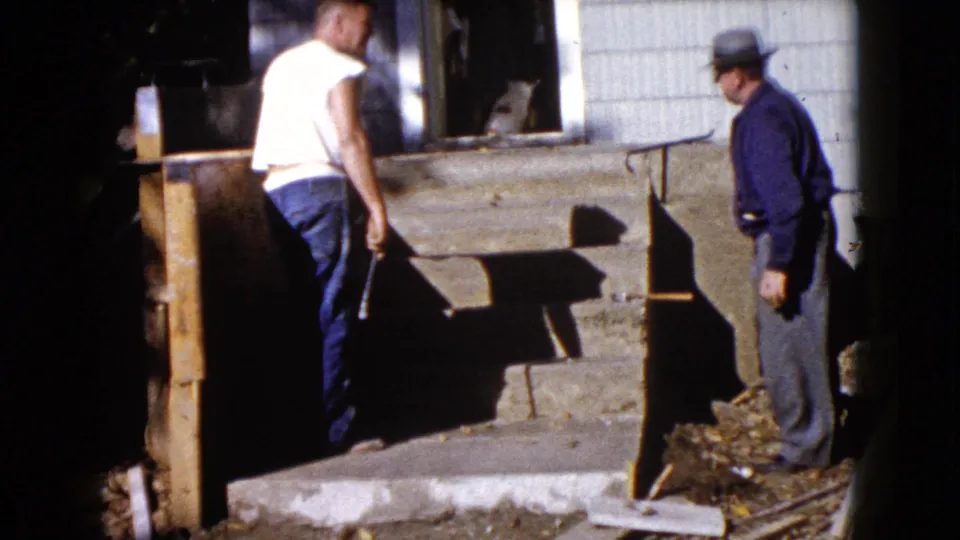 At the end of the clip, two men stand by the wooden exterior steps outside the Wauconda house, with the dog still visible behind them.