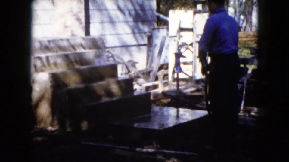 The man appears to continue washing exterior concrete steps in a residential Wauconda yard, filmed on 8mm in 1960.