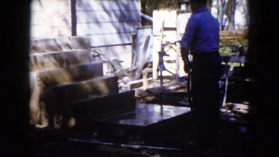 A man remains beside wet concrete steps and outdoor items in a Wauconda, Illinois residential yard in 1960.