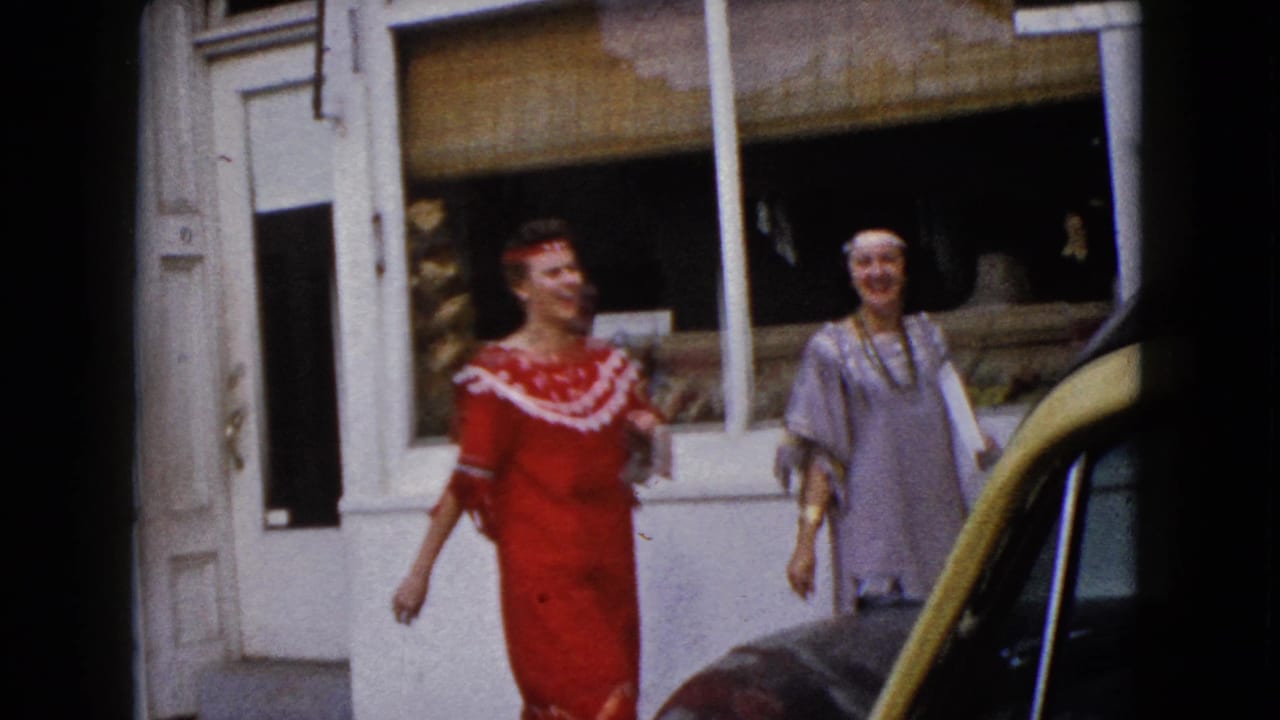 A woman in a red costume walks along the sidewalk outside a Wauconda storefront, with another costumed woman visible behind her.