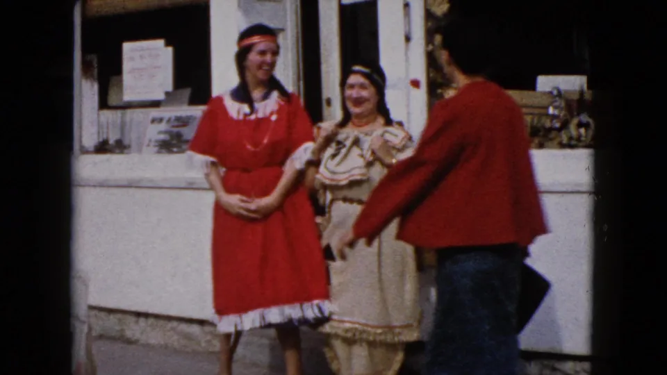 In Wauconda, Illinois in 1960, two costumed women stand outside a storefront as a third woman in red faces them.