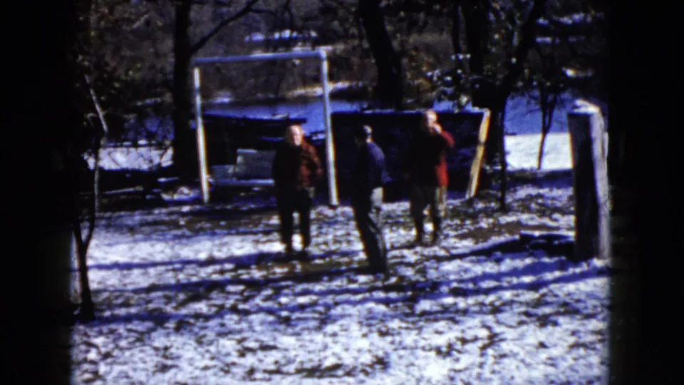 In this Wauconda winter yard frame, three adults stand by a white goal frame while the right-side figure turns toward the camera.