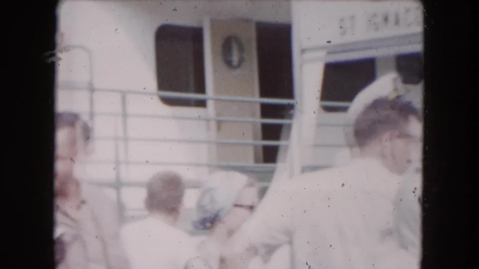 1961 8mm home-movie frame from Buffalo metadata showing passengers near a boat cabin, railings, windows, and a ST IGNACE sign.