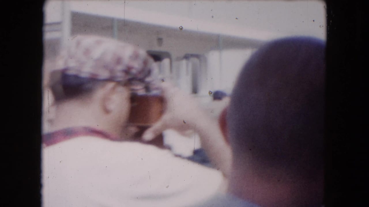 Close deck view of passengers, including a man in a patterned cap holding a camera or object near his face.