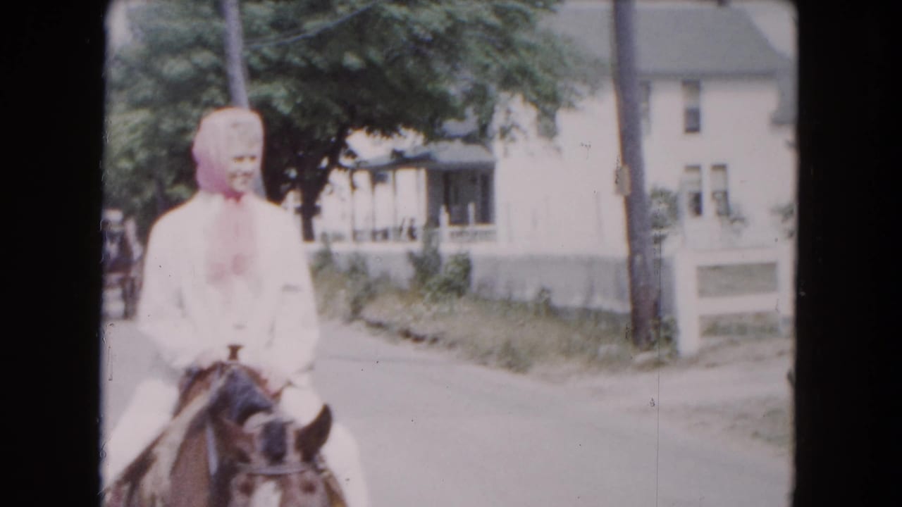Woman in a pink kerchief rides a horse along a Buffalo residential street in the 1961 8mm footage.