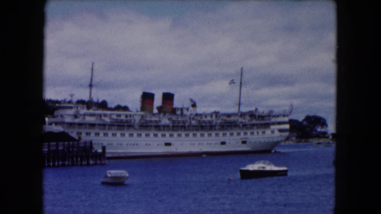 The docked passenger ship remains centered at the Buffalo waterfront, with pier pilings at left and two small boats in the foreground.