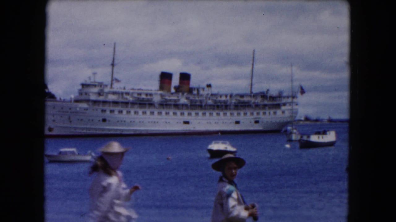 1961 Buffalo harbor view with a large white passenger ship, twin funnels, small boats, and two visitors near the water.