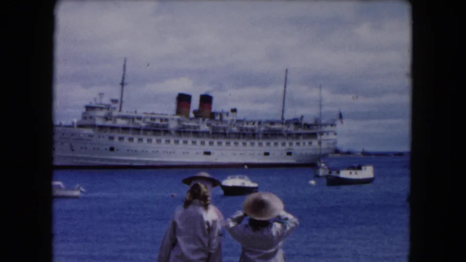 1961 Buffalo waterfront home-movie frame showing visitors watching a large white passenger ship across the harbor.