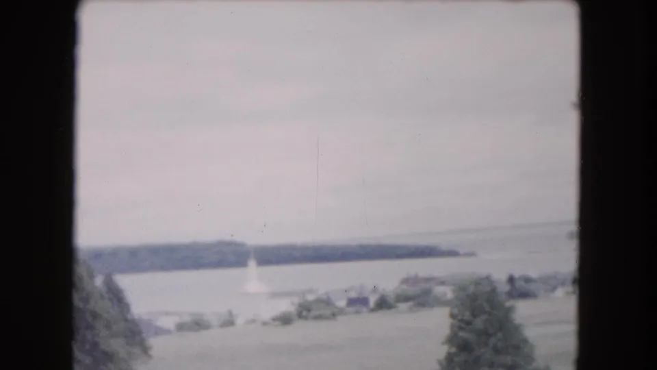 1961 Buffalo-area shoreline view showing open water, wooded land, scattered buildings, and a small pale structure near the water.