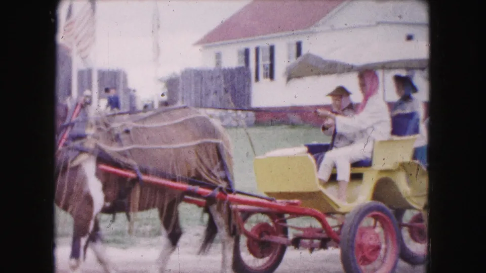 Passengers, including a woman in a pink headscarf, ride in a yellow carriage in 1961 Buffalo home-movie footage.