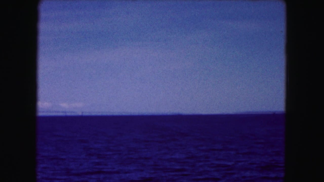 Buffalo-area 1961 home-movie frame showing open water, pale sky, and a faint distant shoreline.