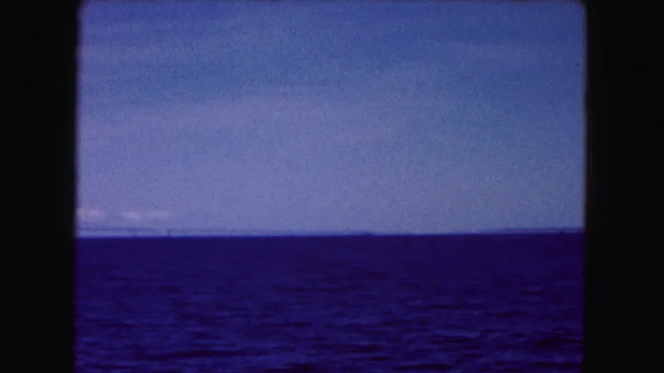 Buffalo-area 1961 home-movie frame showing open water, pale sky, and a faint distant shoreline.