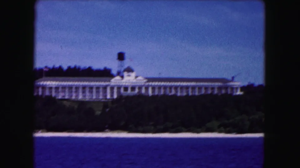 1961 Buffalo-area waterfront view of a long white building among trees with a small water tower visible above the roofline.