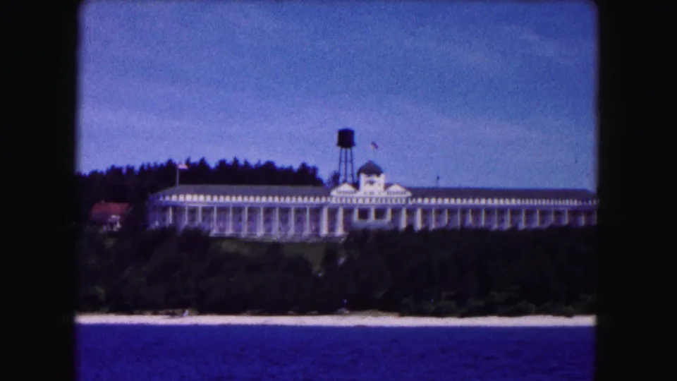 1961 Buffalo lakeside exterior on 8mm film, with a long white building, gray roof, cupola, water tower, trees, and shoreline.