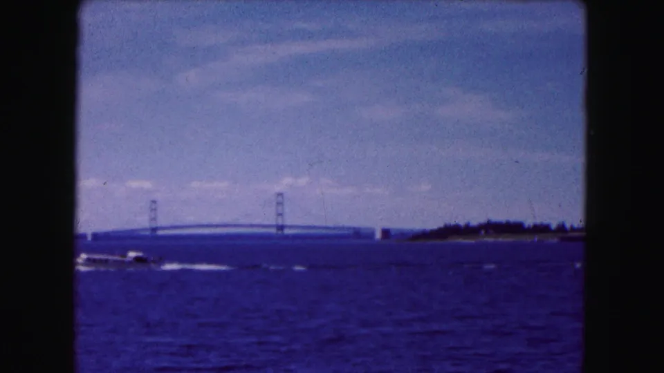1961 8mm home-movie frame with the motorboat partly leaving view and the bridge still visible beyond the water.