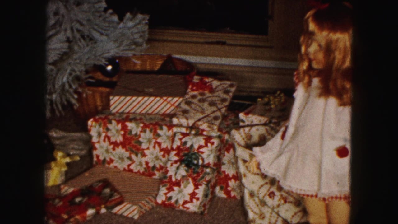 1961 Buffalo holiday interior with wrapped gifts on the carpet and the edge of a dressed doll beside them.