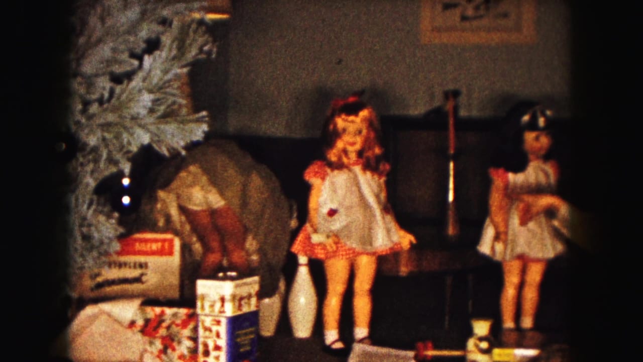 Christmas living room with dolls, toy bowling pins, wrapped gifts, and a decorated artificial tree.
