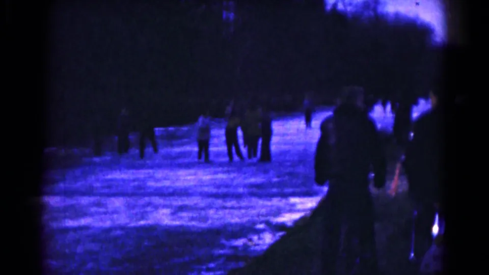 Low-light 1961 home-movie view of people skating away across a blue-lit rink in Hagerstown.