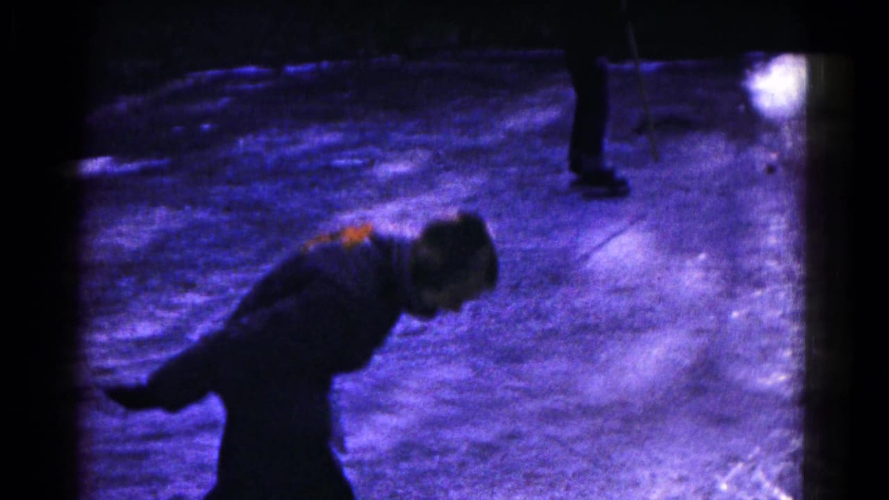 Bundled skater bends forward on a dark frozen lake surface.