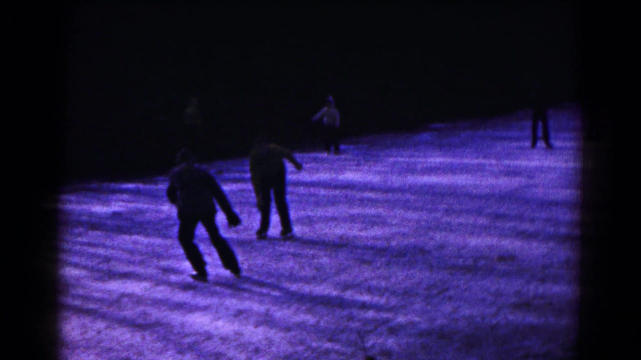 Night skating scene in Hagerstown, Maryland, with two central figures silhouetted against purple-blue ice.