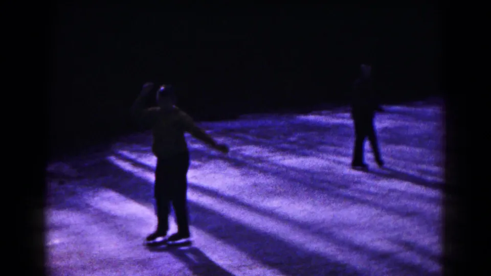 1961 night skating frame with a foreground skater silhouetted on purple-lit ice and another skater to the right.