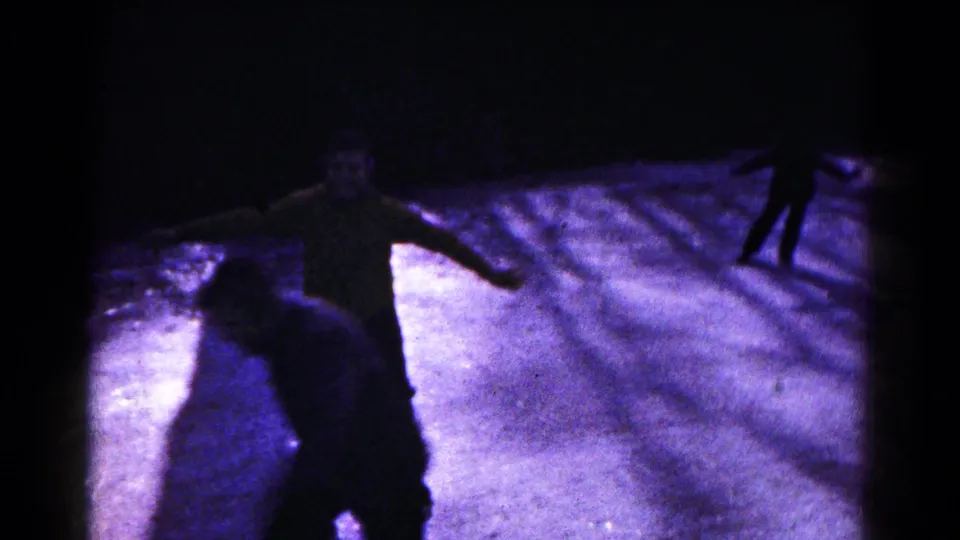 Multiple silhouetted skaters cross a frozen surface, with one figure closer to the camera in 1961 Hagerstown footage.