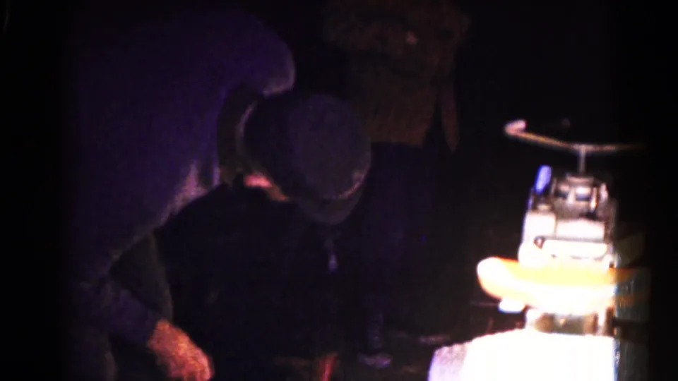 A closer figure appears near the camera beside a bright, indistinct object during the 1961 Hagerstown skating footage.