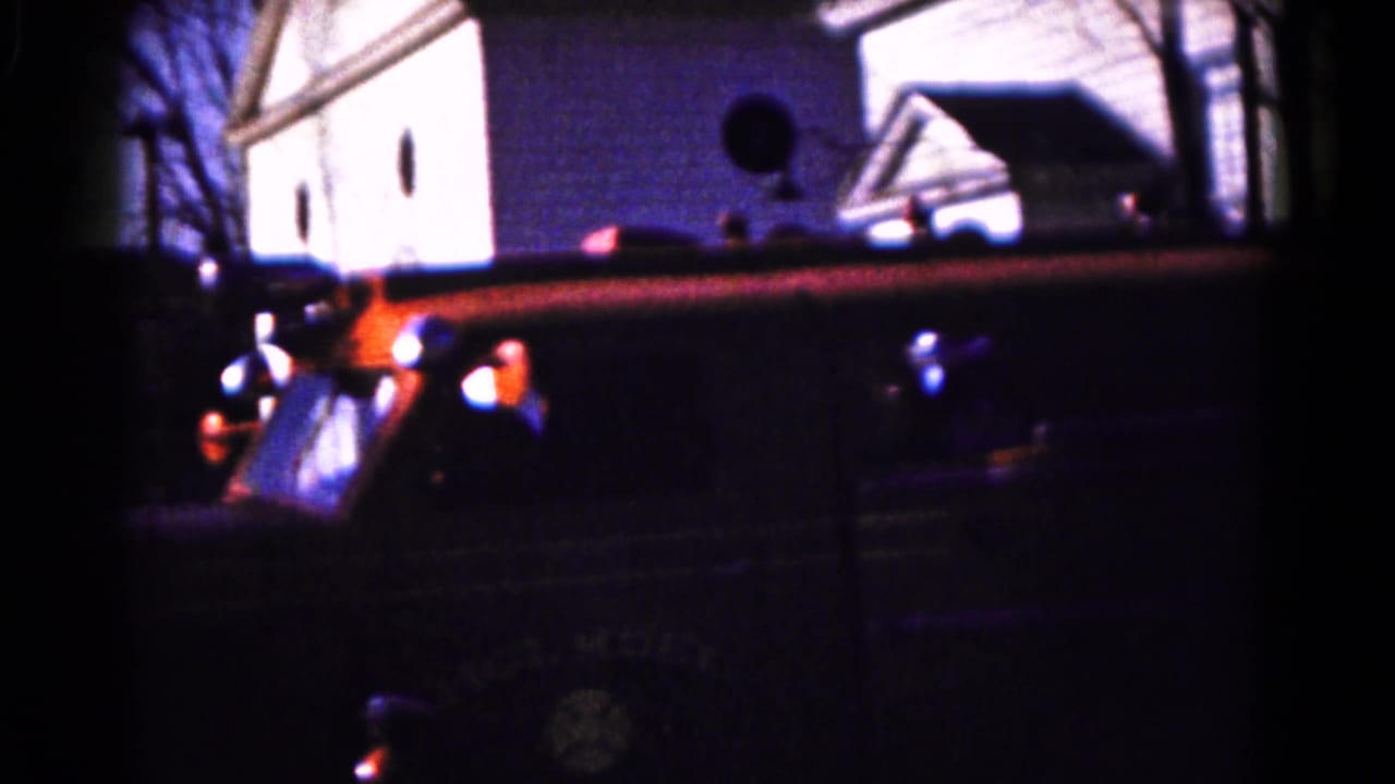Vintage fire engine in Hagerstown, Maryland, seen from the side as it passes a residential block in 1961 home-movie footage.