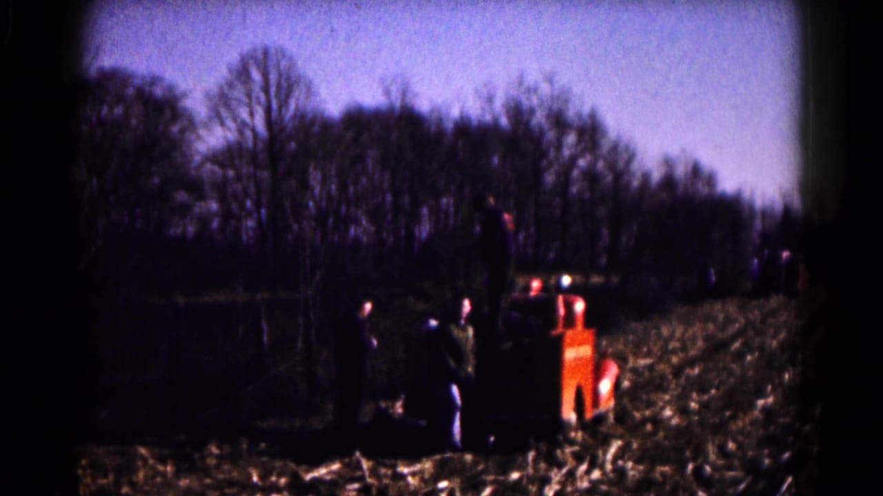 1961 8mm frame from Hagerstown metadata showing a red fire truck with people nearby in a harvested farm field.
