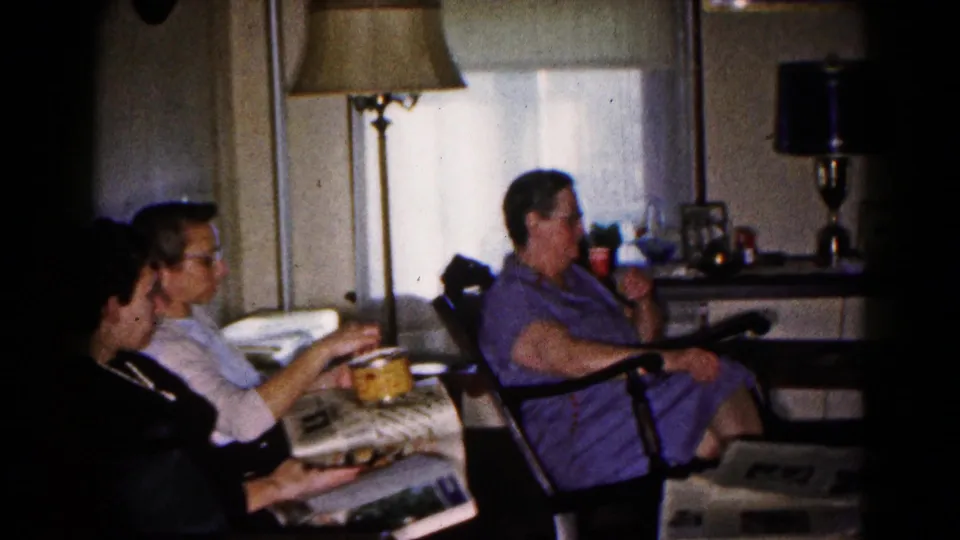 Adults in a Hagerstown living room appear to read and snack while seated near curtained windows, side tables, and period lamps.