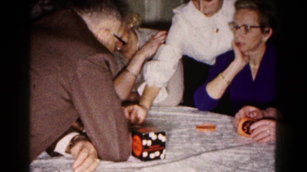 Adults in a 1961 Hagerstown kitchen focus on a tabletop game with orange pieces and a patterned box.