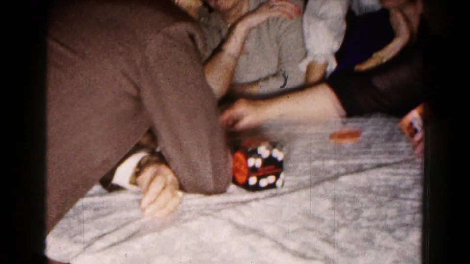 The 1961 indoor party scene shows hands and arms around a table with a dice cup and small game pieces visible.