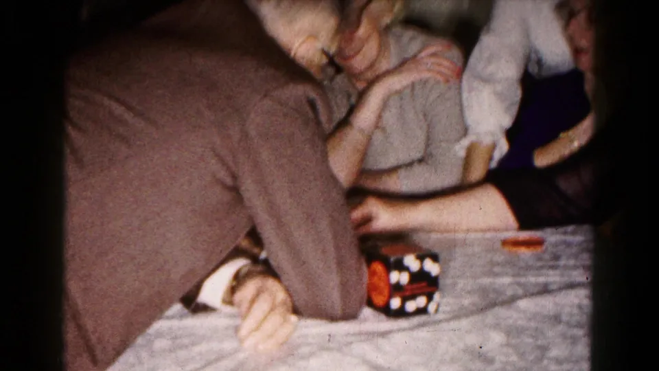 Older adults in 1961 Hagerstown footage lean toward the table as the dice game continues inside a private room.